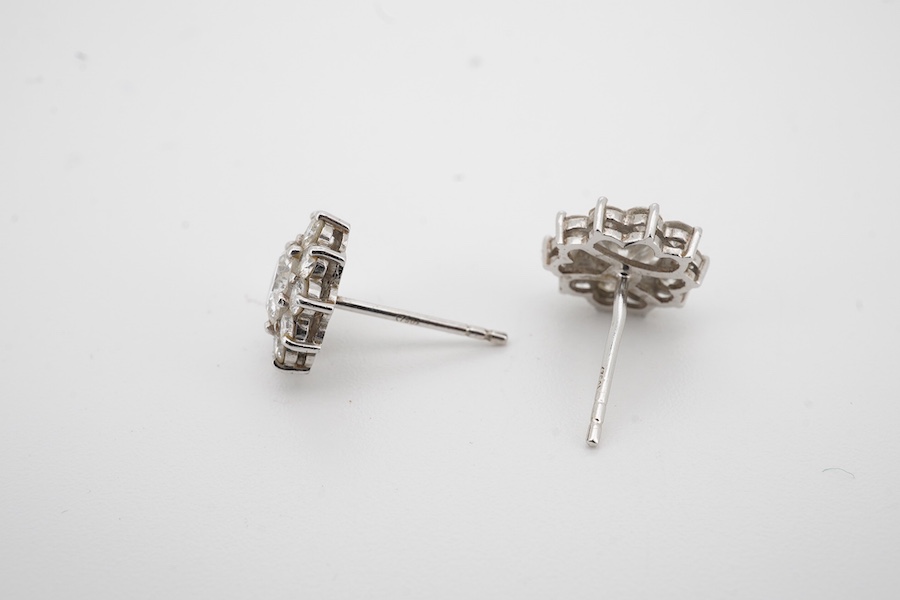 A pair of white metal (stamped 750) and diamond cluster set flower head ear studs, the central stone diameter approximately 6.5mm, overall diameter 9mm, gross weight 2.8 grams, no butterflies. Condition - fair to good